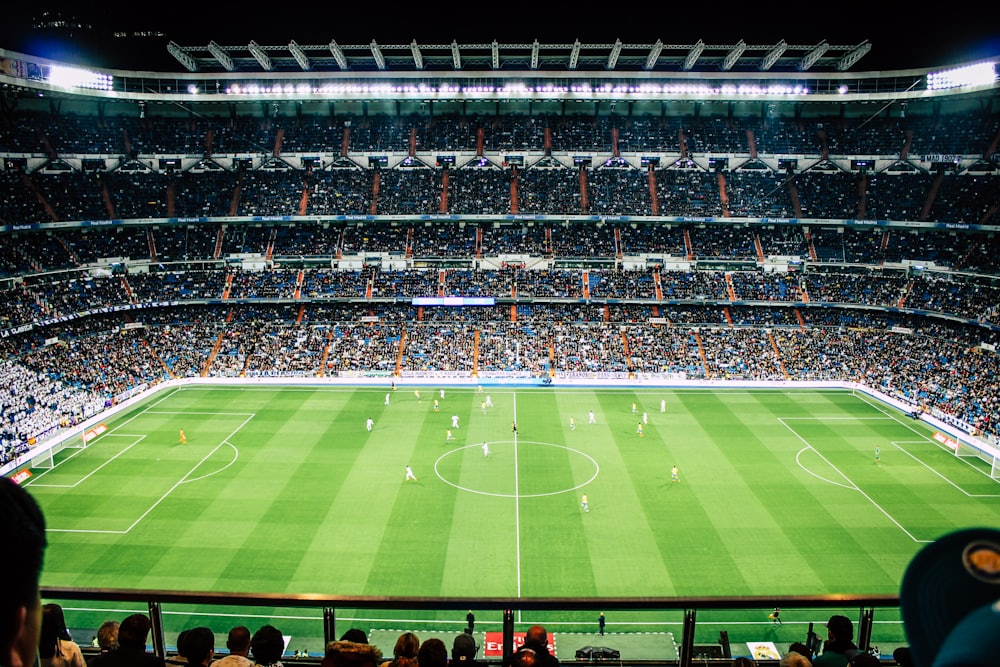 Stadion sepak bola dengan lampu sorot menyala pada pertandingan malam